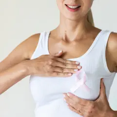 Kobieta z różową wstążką na piersi, symbolizującą wsparcie i świadomość raka piersi. Dba o siebie po operacji oszczędzającej pierś.