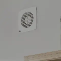 Aspiratore centrifugo o elicoidale bianco montato su parete grigia, accanto a barattoli di pasta.