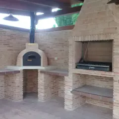 Un barbecue in muratura fai da te con forno a legna e griglia, perfetto per cene all'aperto.