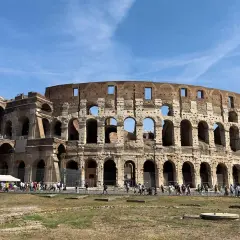 Il Colosseo, una delle principali attrazioni di Roma, 10 cose da vedere. Turisti ammirano l'anfiteatro romano sotto un cielo azzurro.
