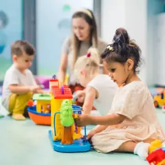 Dzieci bawią się zabawkami w żłobku, gdzie dofinansowanie do żłobka ułatwia opiekę nad najmłodszymi.