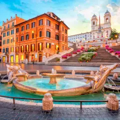 Fontaine de la Barcaccia et l'escalier d'Espagne à Rome au lever du soleil, avec des fleurs colorées.