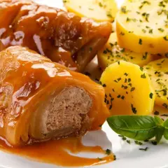 Pyszne gołąbki z mięsem i ryżem w sosie, podane z ziemniaczkami. Idealne danie, by dowiedzieć się, jak zrobić gołąbki z mięsem i ryżem w piekarniku.