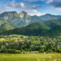 Majestatyczny Giewont, którego wysokość robi wrażenie, góruje nad zieloną doliną pełną domów i lasów.
