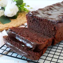 Wilgotna babka kakaowa z polewą czekoladową, pokrojona na kromki, prezentuje się apetycznie.