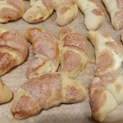 Rogaliki z masą serową, posypane cukrem, pieczone na papierze.