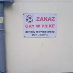 Tabliczka z przekreśloną piłką informuje o zakazie gry w piłkę pod oknami i przy trzepaku.