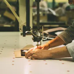 Mains guidant un tissu sous une machine à coudre, créant une pièce sans couture.