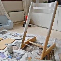 Måla om Stokke stol med vit färg. Trädelar och pensel ligger på tidningspapper.