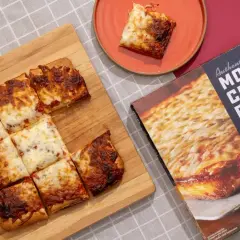 Pokrojona na kwadraty, gorąca pizza mrożona z boxa Motor City Pizza Co. na desce.