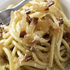 Ein Teller Pasta mit knusprigen Speckwürfeln, die zeigen, was ist Guanciale: luftgetrockneter Schweinebackenspeck, der für den authentischen Geschmack sorgt.