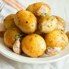 Patate al microonde in 3 minuti, condite con aglio e erbe aromatiche, pronte per essere gustate.