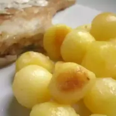 Une assiette de poisson grillé avec une généreuse portion de pomme de terre parisienne, dorée et appétissante.