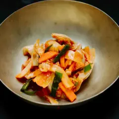 Frisch zubereitetes asiatisches Essen: Kimchi mit Karotten und Frühlingszwiebeln in einer Schüssel.