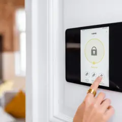 Main d'une personne touchant un écran tactile pour activer un système d'alarme filaire ou sans fil.