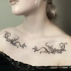 Delikatny tatuaż ornament damski na obojczykach, przypominający koronkę.