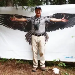 Mann mit ausgebreiteten Armen vor einem Banner mit einem Bartgeier. Ein Zeichen für Bartgeier in Deutschland.