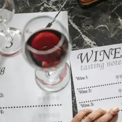 Degustacja wina: notatki z degustacji, kieliszki z czerwonym winem i formularz do zapisywania wrażeń.