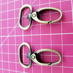 Dos mosquetones de latón envejecido, perfectos para tu mochila o llavero.
