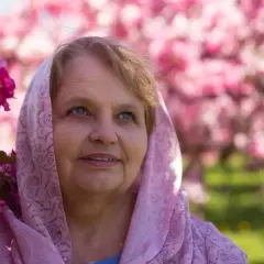Uśmiechnięta Zuzanna w różowym szalu, otoczona kwitnącymi drzewami. Piękny dzień na imieniny Zuzanny.
