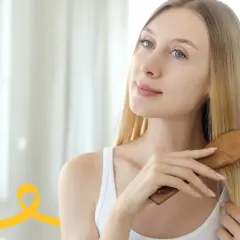 Kobieta z długimi blond włosami szczotkuje je drewnianą szczotką, przygotowując się do tego, jak myć głowę.