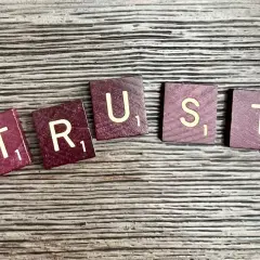 Litery "TRUST" ułożone na drewnianym tle. Brak zaufania w związku czy to ma sens?