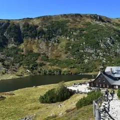 Schronisko Samotnia nad Małym Stawem w Karkonoszach. Kamienista ścieżka prowadzi do schroniska, obok którego rozciąga się malownicze jezioro.