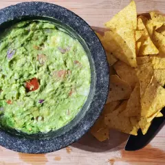 Färdiggjord guacamole i en mortel, redo att serveras med tortillachips. Ett enkelt guacamole recept för alla.