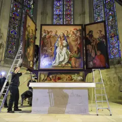 Mitarbeiter montieren einen Flügel des Altars in der Kirche. Buntglasfenster und Skulpturen zieren die Kathedrale.