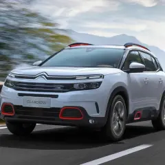 Biały Citroen C5 Aircross z czerwonymi akcentami pędzi po drodze. Wiele osób szuka o nim **citroen c5 aircross opinie**.