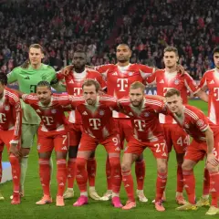 Drużyna Bayern Monachium – zawodnicy w czerwono-białych strojach pozują do zdjęcia na murawie stadionu, z trybunami pełnymi kibiców w tle.