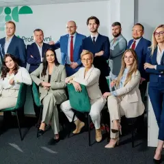 Zespół prawników w garniturach pozuje do zdjęcia w nowoczesnym biurze.
