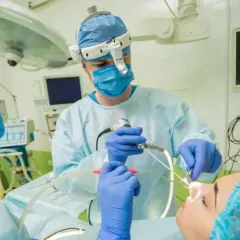 Chirurg wykonuje operację przegrody nosowej, obserwując obraz z endoskopu na monitorze.