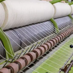 Gros rouleaux de fil blanc sur une machine de filature. Le processus de filature est en cours, transformant la matière première en fil.