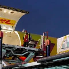 Pracownicy rozładowują samolot DHL. Z jakiego kraju pochodzi ten transport?