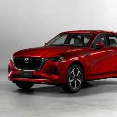 Elegancka, czerwona Mazda CX-60 3.3 Diesel prezentuje swoje dynamiczne linie na tle jasnego studia.