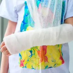 Dziecko z ręką w gipsie i temblaku. Złamany palec wymagał zwolnienia z zajęć.