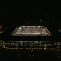 Nocny widok stadionu Górnik Zabrze. Trybuny wypełnione kibicami, widoczny napis "KLUB SPORTOWY GÓRNIK ZABRZE NASZYM ŻYCIEM". Pojemność stadionu robi wrażenie.
