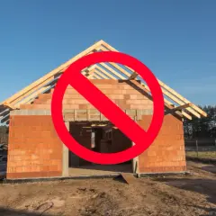 Czerwony znak zakazu na budowie domu z cegły. Oznacza to brak możliwości legalizacji samowoli budowlanej.