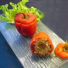 Poivrons farcis à la chair à saucisse, servis sur un plateau en verre avec une feuille de laitue.