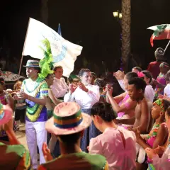 Gruppi calabresi famosi in festa, con costumi colorati e bandiere, celebrano la cultura popolare in un festival vivace.