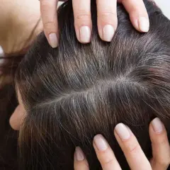 Manos revisan cabello oscuro con hebras grises, como si la leyenda de que si te quitas una cana salen mas fuera cierta.