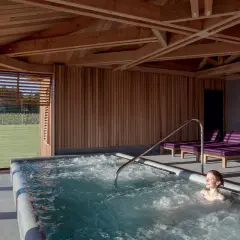 Détente dans un chateau spa à Bordeaux. Une femme profite d'un jacuzzi avec vue sur les vignes.