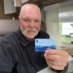 Man håller upp ett AutoPASS-kort för färjor, redo för bila i Norge.