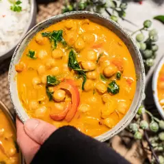 Ein köstliches veganes Curry mit Kichererbsen, Paprika und Spinat in cremiger Sauce, serviert mit Reis.