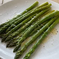 När man ska koka sparris är det viktigt att den blir perfekt. Här ligger en vackert grön, nykokt sparris på ett fat, strödd med flingsalt och peppar.