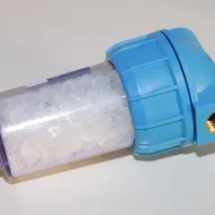 Filtre bleu transparent rempli de cristaux pour l'adoucissement de l'eau.