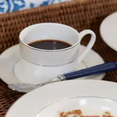 Frukostbricka med kaffe, juice och flingor. En kopp kaffe med en sked, perfekt för att njuta av morgonen. Undrar hur många koppar kaffe per paket?