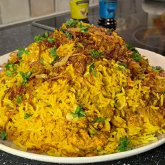 En stor portion gyllene biryani med kyckling, toppad med krispig lök och färsk koriander. Ett perfekt biryani recept för en festmåltid.