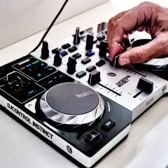 Dłoń DJ-a manipuluje pokrętłem na konsoli Hercules DJControl Instinct.